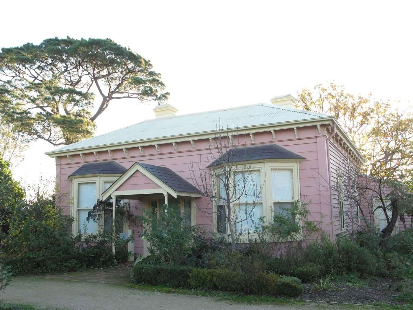 The pink weatherboard farmhouse known as Heide I among trees and garden beds