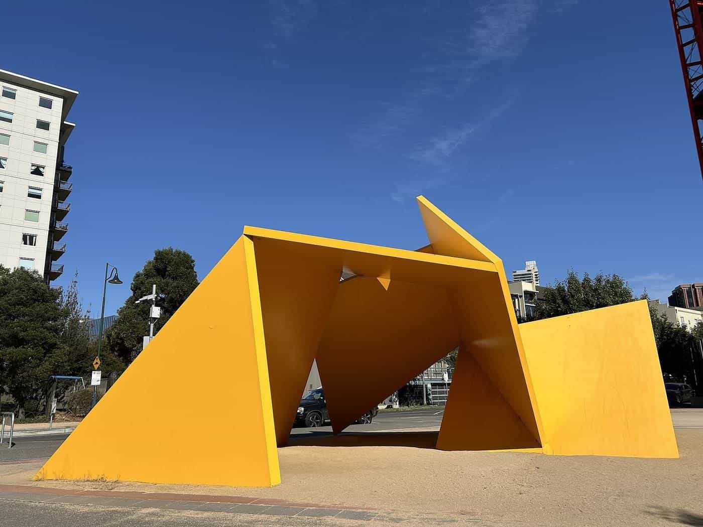 A bright yellow angular steel sculpture against a blue sky in Southbank