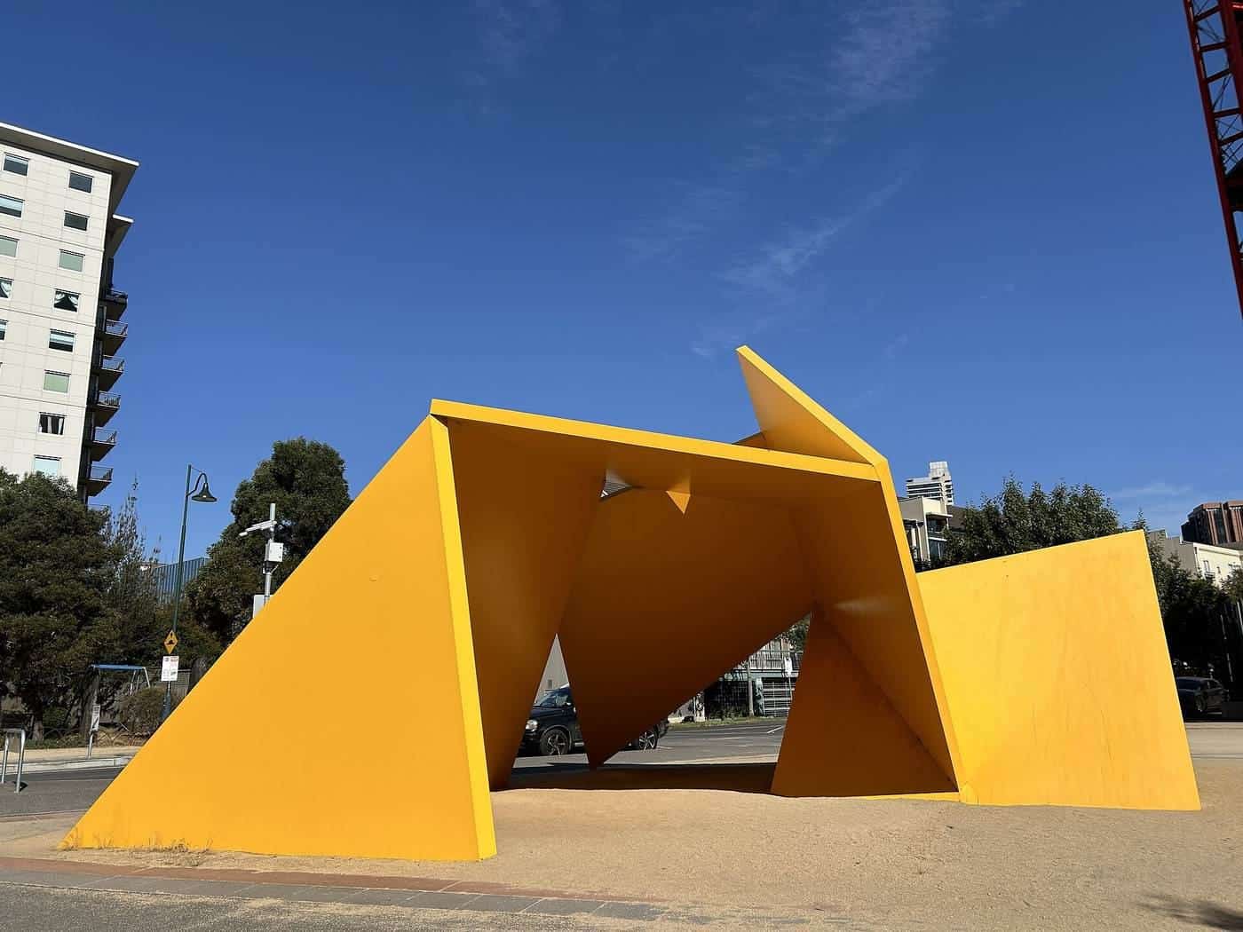 A bright yellow angular steel sculpture against a blue sky in Southbank