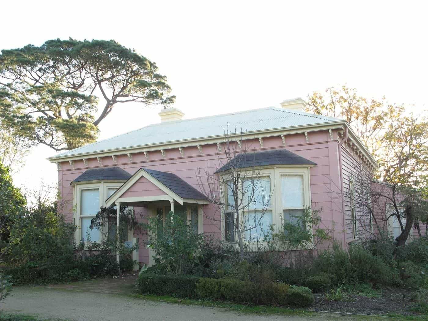 The pink weatherboard farmhouse known as Heide I among trees and garden beds